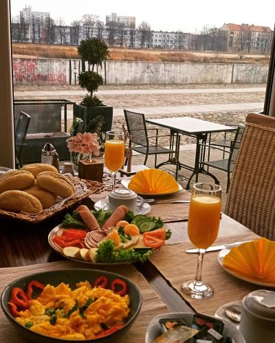 uma mesa com pratos de comida e copos de suco de laranja em Pension Oderblick em Frankfurt an der Oder