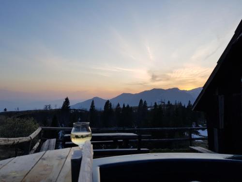 a glass of wine sitting on a table with the sunset at Chalet Encijan - Velika planina in Stahovica