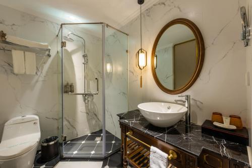 a bathroom with a sink and a glass shower at Hanoi Tirant Hotel in Hanoi