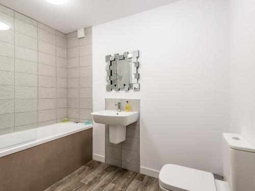 a bathroom with a sink and a toilet and a bath tub at Casa Fresa - Castle Heights Apartment in Dundee