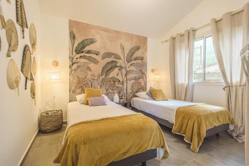 two beds in a room with a painting on the wall at Ti Kaz Lontan - La Rivière in Saint-Louis