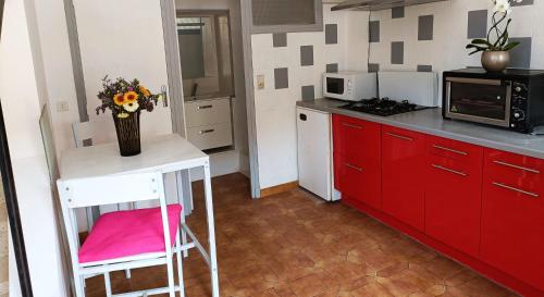 a kitchen with red cabinets and a vase of flowers on a table at Jolie studio récemment rénové in Marseillette