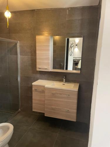 a bathroom with a sink and a toilet and a mirror at Hôtel La Grillade in Moroni