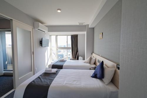 a hotel room with two beds and a window at HOTEL STATE TENNOJI in Osaka