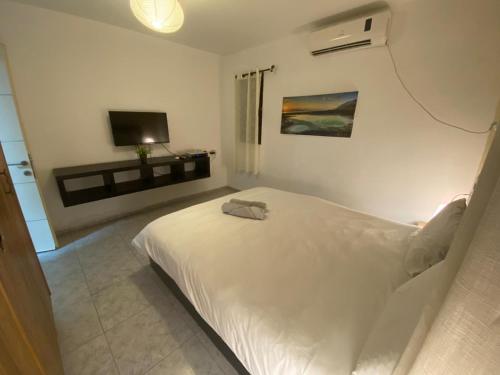 a white bedroom with a bed and a tv at Adi in Arad