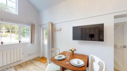 a dining room with a table and a tv on the wall at Hidden Jewel Retreat in Budleigh Salterton