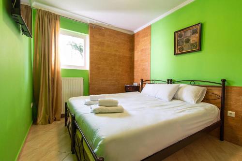 a bedroom with a large bed with green walls at Franceska's guest house in Artemida
