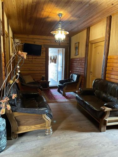 a living room with leather furniture and a chandelier at Kurėnų Užeigos Svečių Namai in Kurėnai
