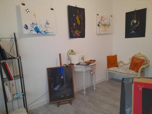 Habitación con escritorio, silla y pinturas en la pared. en La chambre de Garance et ses couleurs d'art en Saint-Pol-de-Léon