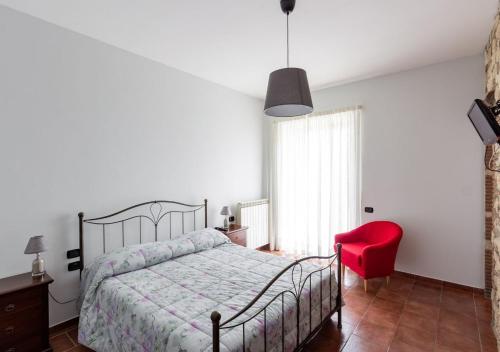 Agriturismo Il Sentiero degli Ulivi - Irpinia في Venticano: غرفة نوم بسرير وكرسي احمر
