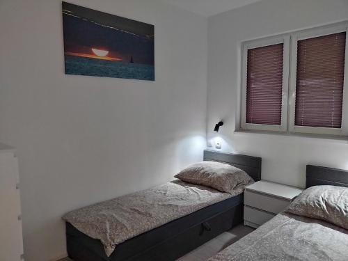 a bedroom with two beds and a picture on the wall at Domek parterowy apartamentowy Ostoja in Rewal