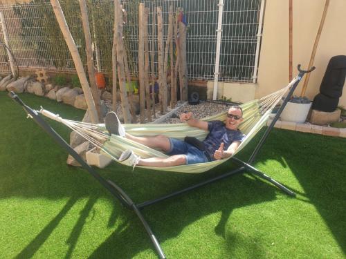 a man laying in a hammock on the grass at Finca Olivar de Castilla - Sun&Colors in Segovia