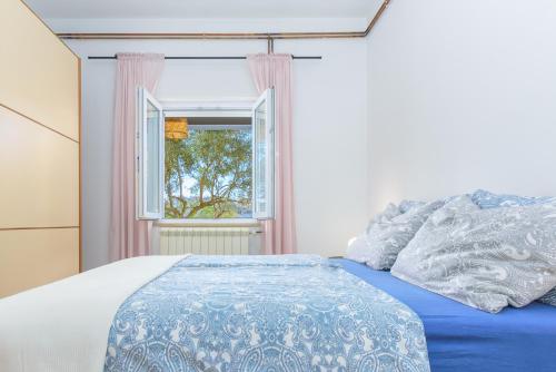 sypialnia z niebieskim łóżkiem i oknem w obiekcie Apartment Macan, beautiful green oasis w Puli