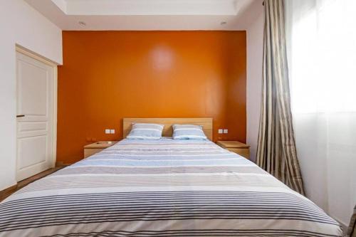 a bedroom with a large bed with an orange wall at Douala-Bonapriso: Superbe Appartement in Douala