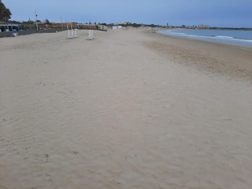 a sandy beach with umbrellas and the ocean at Casa Romano - Marina di Modica in Marina di Modica