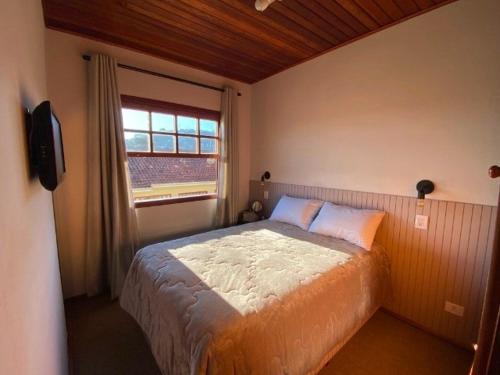 um quarto com uma cama grande e uma janela em Seu ap em Campos do Jordão em Campos do Jordão