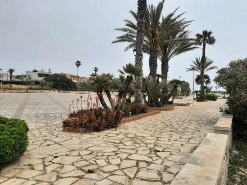 a cobblestone street with palm trees and plants at Casa Romano - Marina di Modica in Marina di Modica