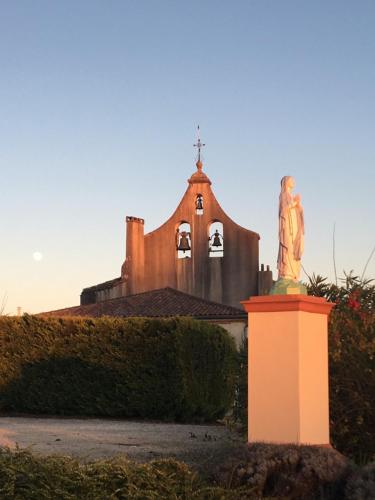 a church with a statue in front of a building at Aux Coteaux d'Aussac in L Honor De Cos