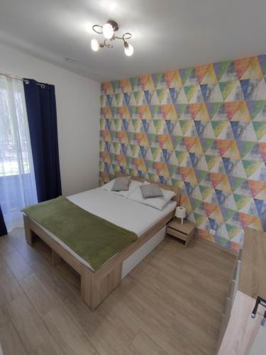 - une chambre avec un lit et un mur coloré dans l'établissement Apartament Białowieski, à Hajnówka