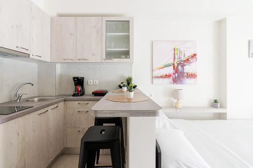 une cuisine avec des placards blancs et un comptoir avec un tabouret dans l'établissement Modern Athens Studio by Cloudkeys, à Athènes