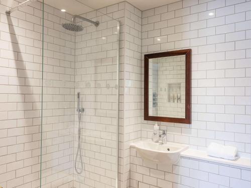 a bathroom with a shower and a sink and a mirror at The Bridge Hotel in Chertsey