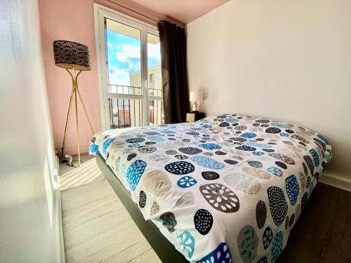 a bedroom with a bed with a patterned comforter at APPART HOTEL DU BOIS DE VINCENNES in Fontenay-sous-Bois