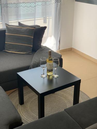 a bottle of wine and two glasses on a coffee table at Apartamento de Ensueño in Garrucha