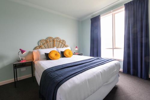 a bedroom with a large bed with two yellow pillows on it at Selina St Kilda Melbourne in Melbourne