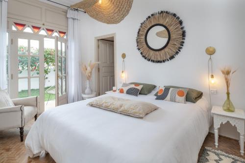 een slaapkamer met een groot wit bed en een spiegel bij Maison Marine in Oualidia