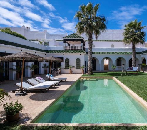 a resort with a swimming pool and palm trees at Maison Marine in Oualidia