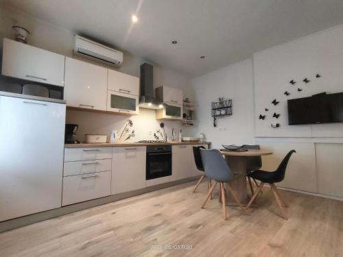 uma cozinha com armários brancos e uma mesa e cadeiras em Studio Placa em Punat