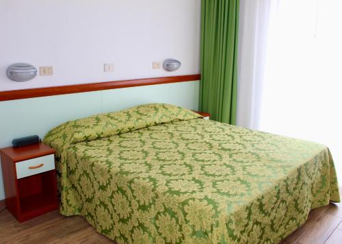 sypialnia z łóżkiem z zieloną kołdrą w obiekcie Hotel Cristina w Grado