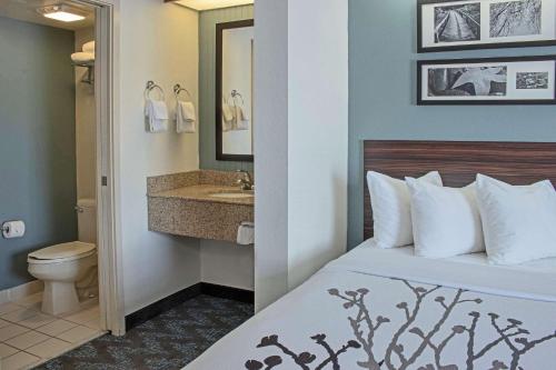 a hotel room with a bed and a sink at Sleep Inn Lake Wright - Norfolk Airport in Norfolk
