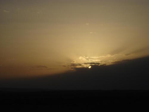 a cloudy sky with the sun hiding behind a cloud at Le Drom'blanc in Mhamid