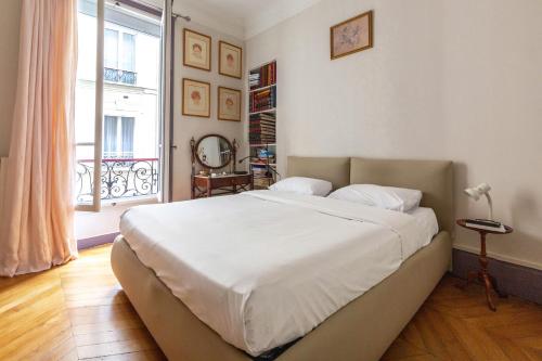 une chambre avec un grand lit blanc et une fenêtre dans l'établissement Veeve - Vintage Violet, à Paris