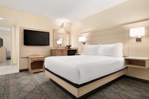 a bedroom with a large white bed and a flat screen tv at Ramada by Wyndham Miramichi New Brunswick in Miramichi