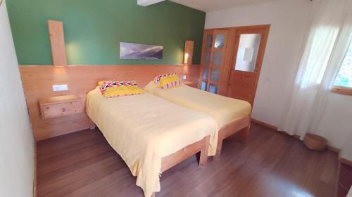two beds in a bedroom with green walls and wooden floors at Casa Cavoquinho in Paul