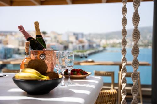 a table with a bowl of fruit and wine glasses at Casa Porto Boutique Hotel - Adults only in Agios Nikolaos