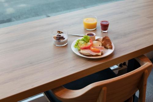 a plate of food on a wooden table with orange juice at Comfort Hotel Børsparken in Oslo
