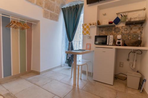 a small kitchen with a table and a microwave at RomAntica in Polignano a Mare