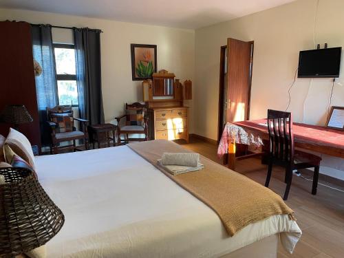 a bedroom with a bed and a desk and a table at Waterberg Accommodation in Modimolle