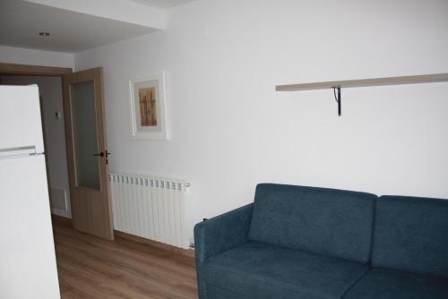 a living room with a blue couch and a door at Apt Nuevos con caballos Fio de Neu Laspaules in Laspaúles