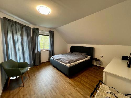 a bedroom with a bed and a chair and a window at Premium Apartment direkt am Golfpark Klopeiner See in Grabelsdorf