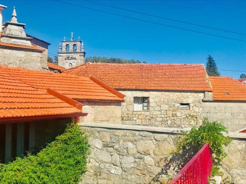 an old stone building with orange roofs and a church at Janelas da Cabreira in Campos