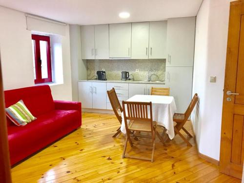 a living room with a table and a red couch at Janelas da Cabreira in Campos