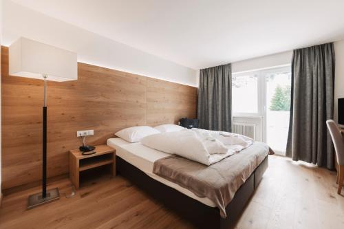 a bedroom with a bed with a wooden wall at Wellness Aparthotel Panorama Alpin - Ferienwohnungen Jerzens im Pitztal in Jerzens