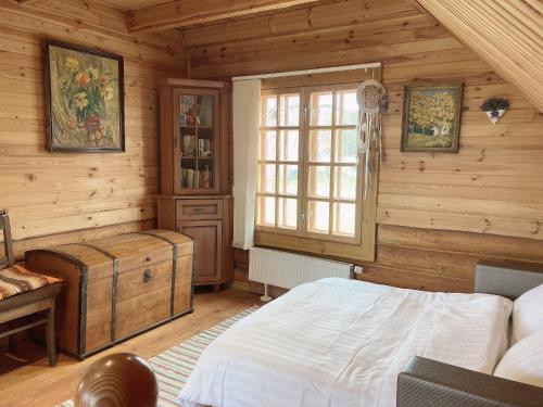 una camera da letto con pareti in legno, un letto e una finestra di Brīvdienu māja Būmaņi a Dreiliņi