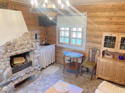 ein Wohnzimmer mit einem Steinkamin und einem Tisch in der Unterkunft Brīvdienu māja Būmaņi in Dreiliņi