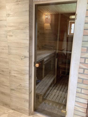 a glass door to a sauna with a wooden bench at Brīvdienu māja Būmaņi in Dreiliņi
