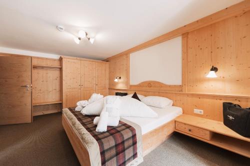 a bedroom with a large bed with wooden walls at Wellness Aparthotel Panorama Alpin - Ferienwohnungen Jerzens im Pitztal in Jerzens